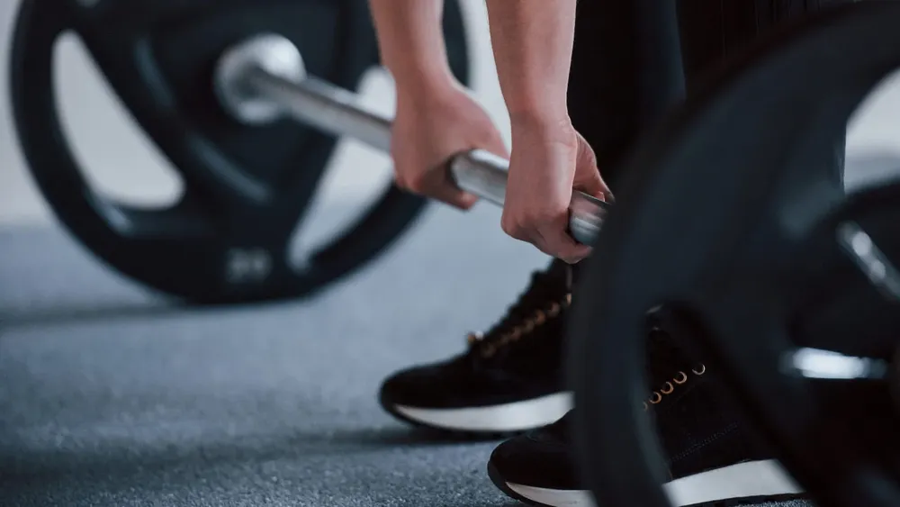 Persona realizando entrenamiento de fuerza con pesas en un gimnasio. Créditos. Freepik
