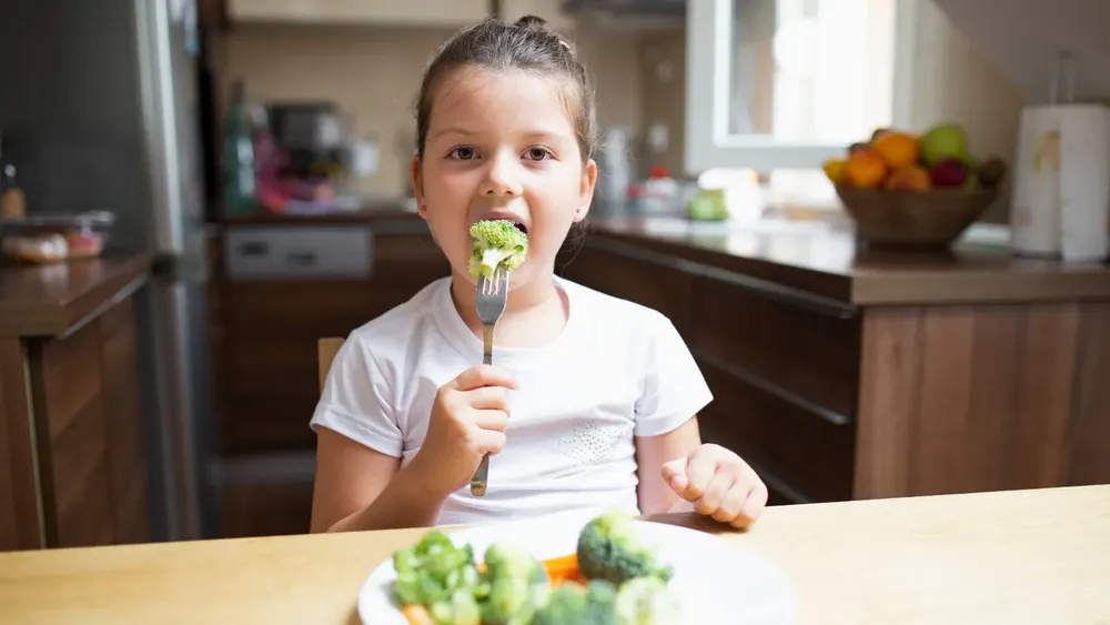 Niña comiendo brocoli y verduras en su plato. Créditos: Freepik